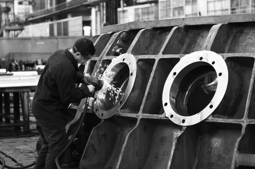 Photo noir et blanc : soudeur sur une pièce industrielle